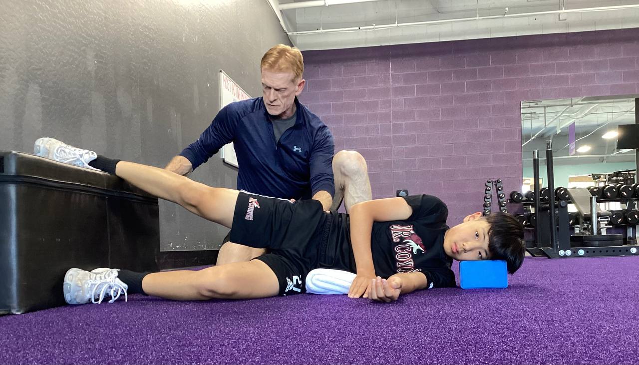 Robert doing hands-on hip mobility work with an athlete on the floor