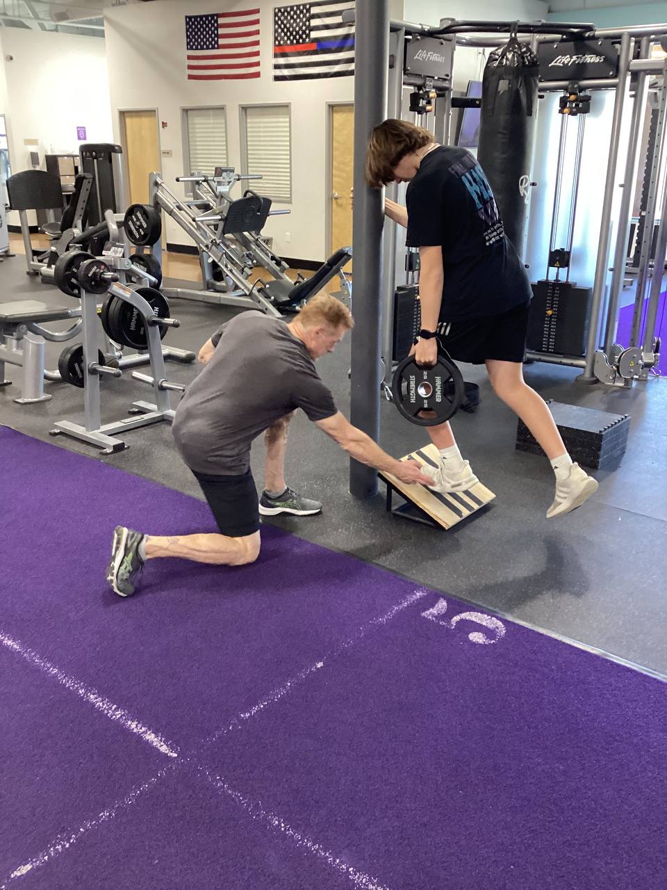 Robert and an athlete training together on purple turf — energy and action
