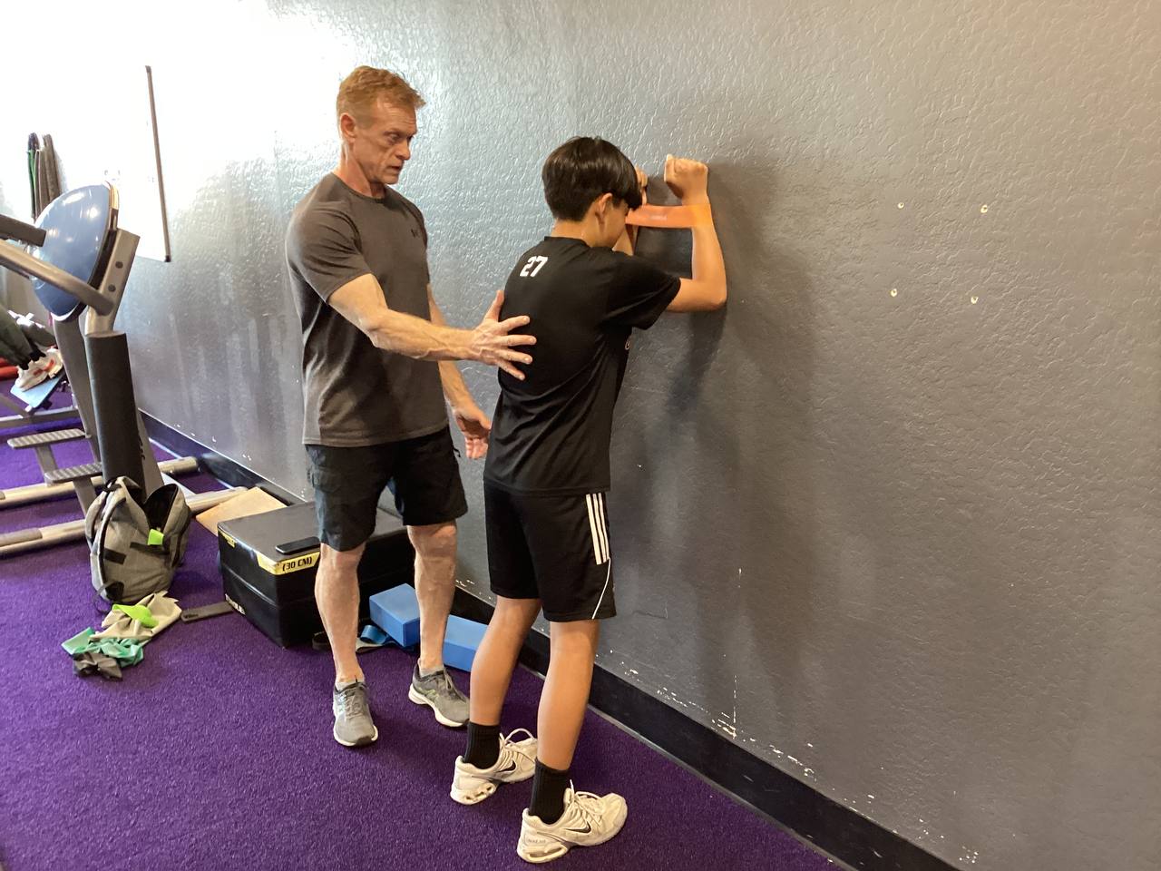 Robert McLean with focused expression, coaching an athlete through a wall drill